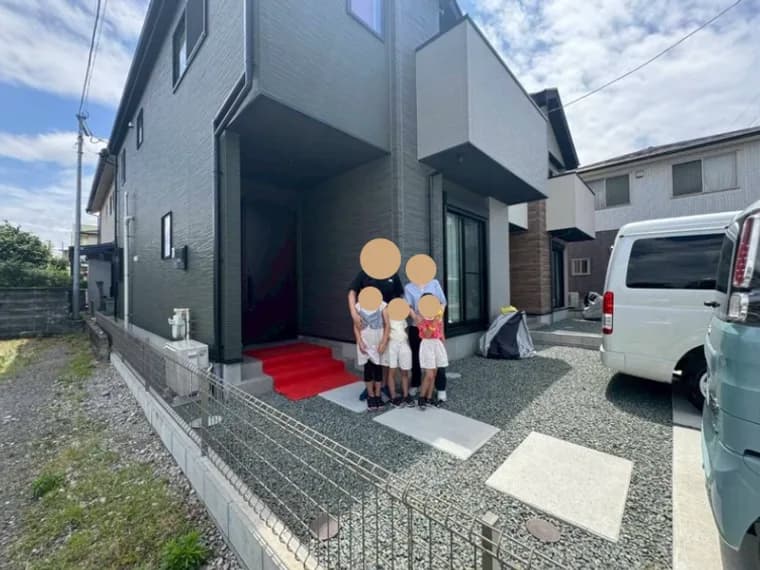 お引渡しの日、新築建売住宅の玄関前で記念撮影をするご家族